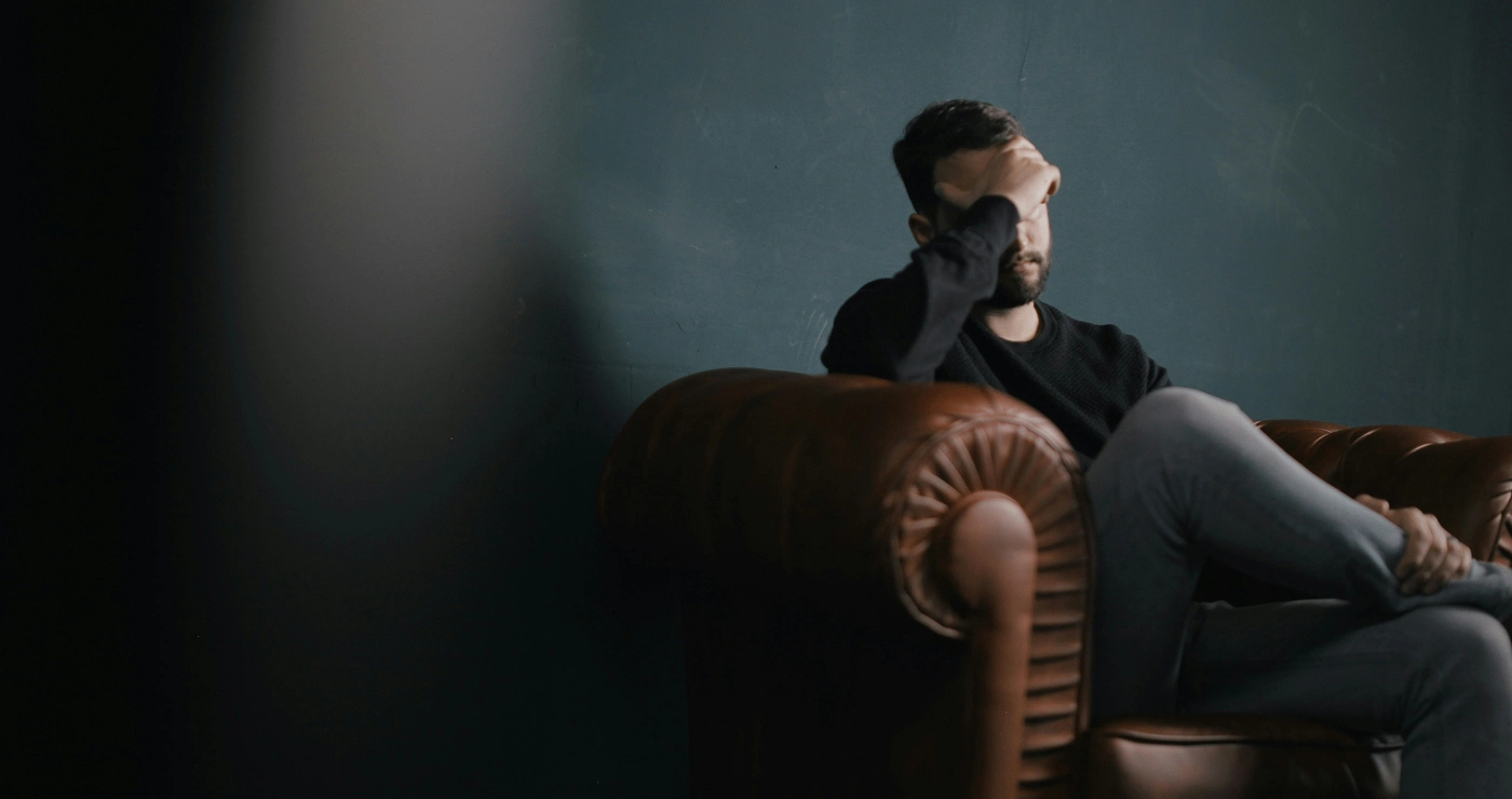 a man sitting on a couch with his hand on his face