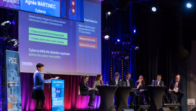 Woman presenting on stage to a seated panel at PSCC Innovation Forum with slides about Cyberna detection method.