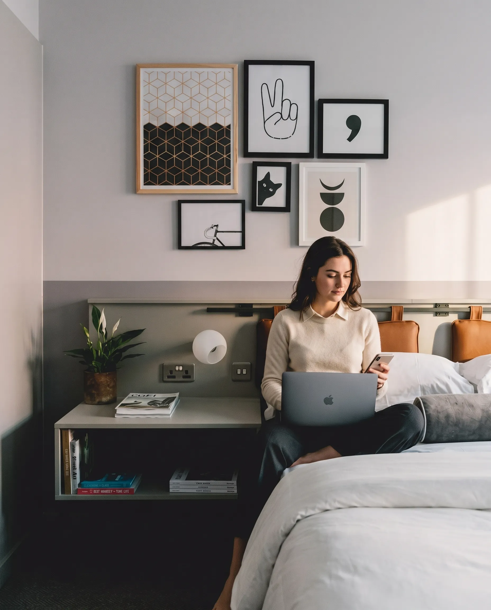 Guest working on a laptop at the edge of the bed in a LEVEN apartment