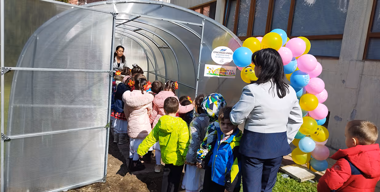 Raffiti Agency,” showcasing public art and urban beautification. Kinderen in een greenhouse voor educatieve gardenactiviteit — Joven kinderen, met volwassenen, in een nieuwe geïnstalleerde greenhouse decoratie met cheerende balonen en signs van “ENERGO-PRO”