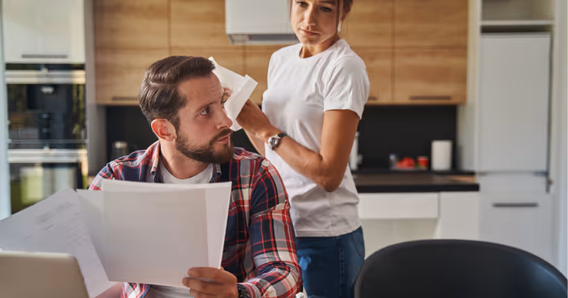 A man and a woman sitting in front of a laptop with documents in their hands