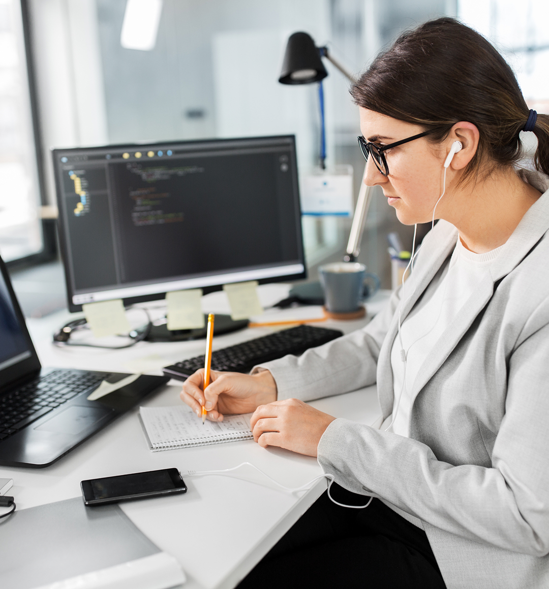female programmer working on computer and writing code in modern office