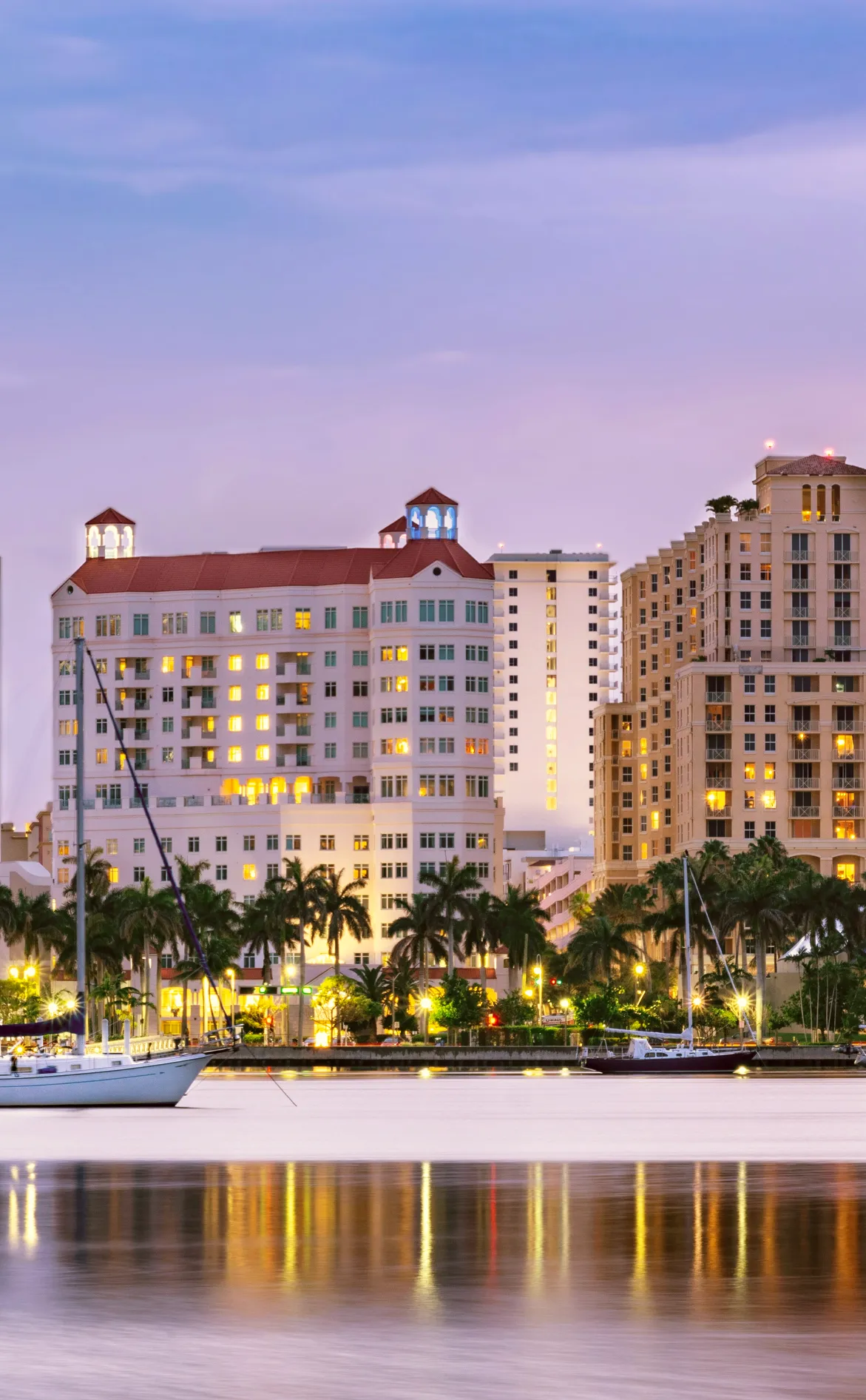 Waterfront city view with boats and illuminated buildings at dusk