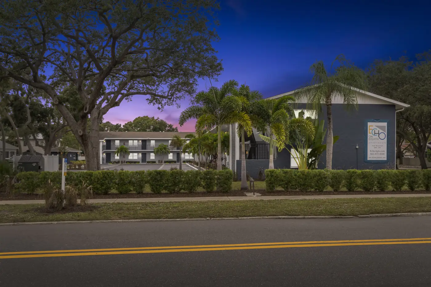 Echo on Eighth apartments at 785 N Osprey Ave, Sarasota FL, at dusk with palms and monument signage