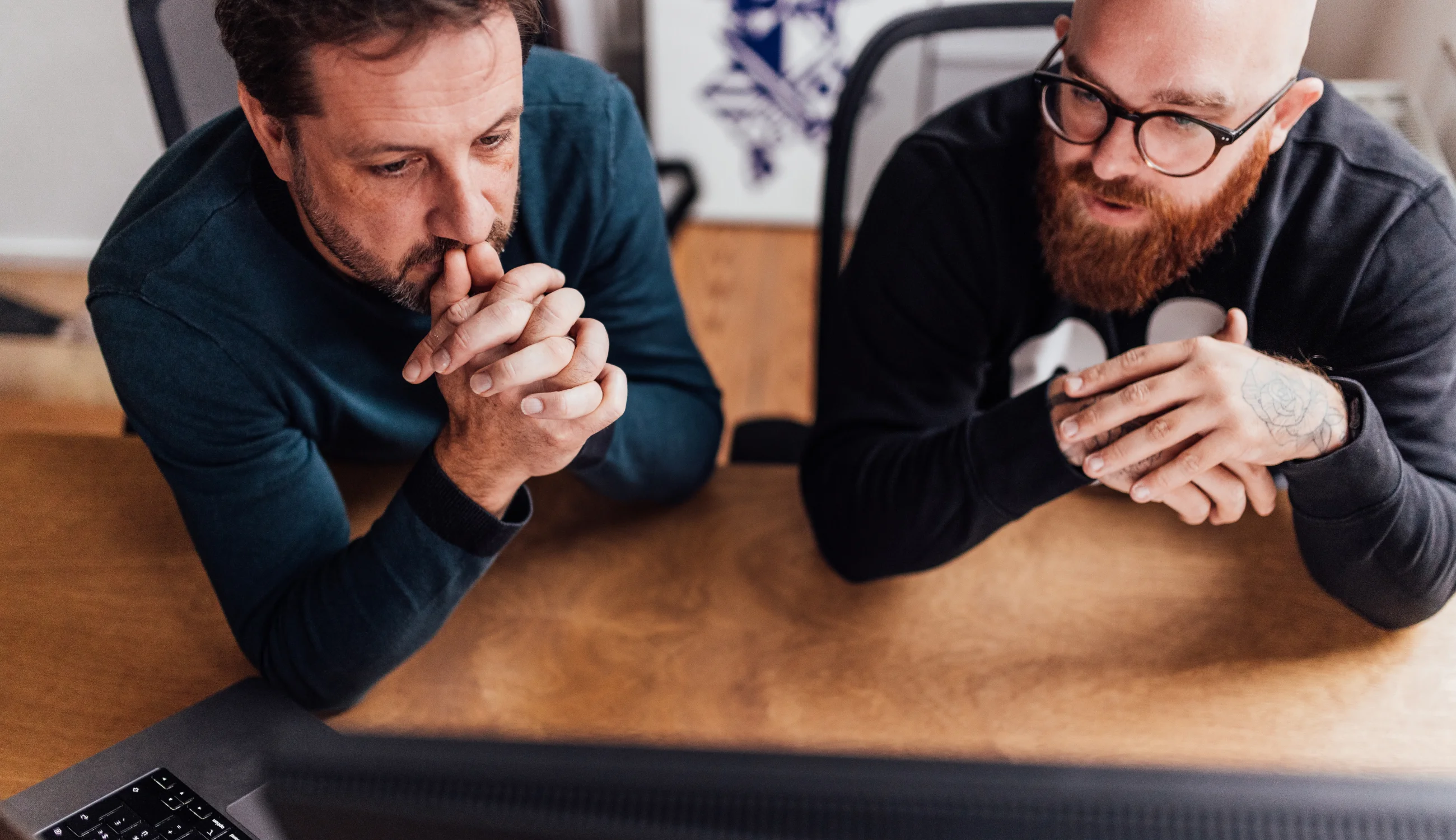 Merkstrateeg Jan en Creative Director Rik in overleg achter een computerscherm vanuit vogelperspectief gefotografeerd.
