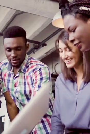 Diverse colleagues laughing together while working in an office kitchen