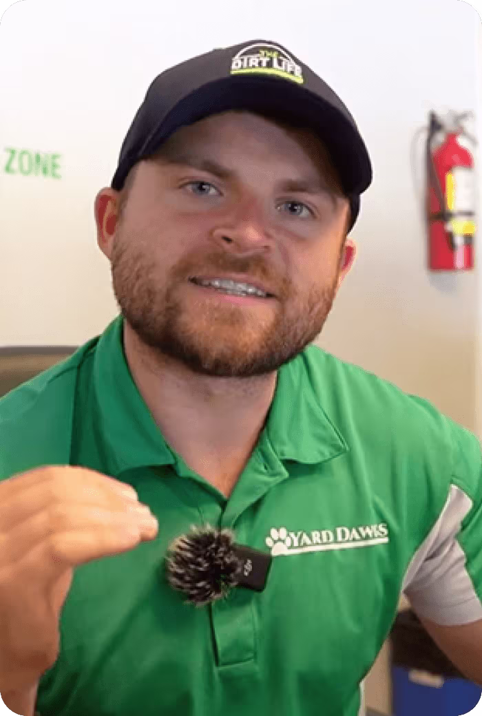 Man in green shirt holding pinecone near fire extinguisher