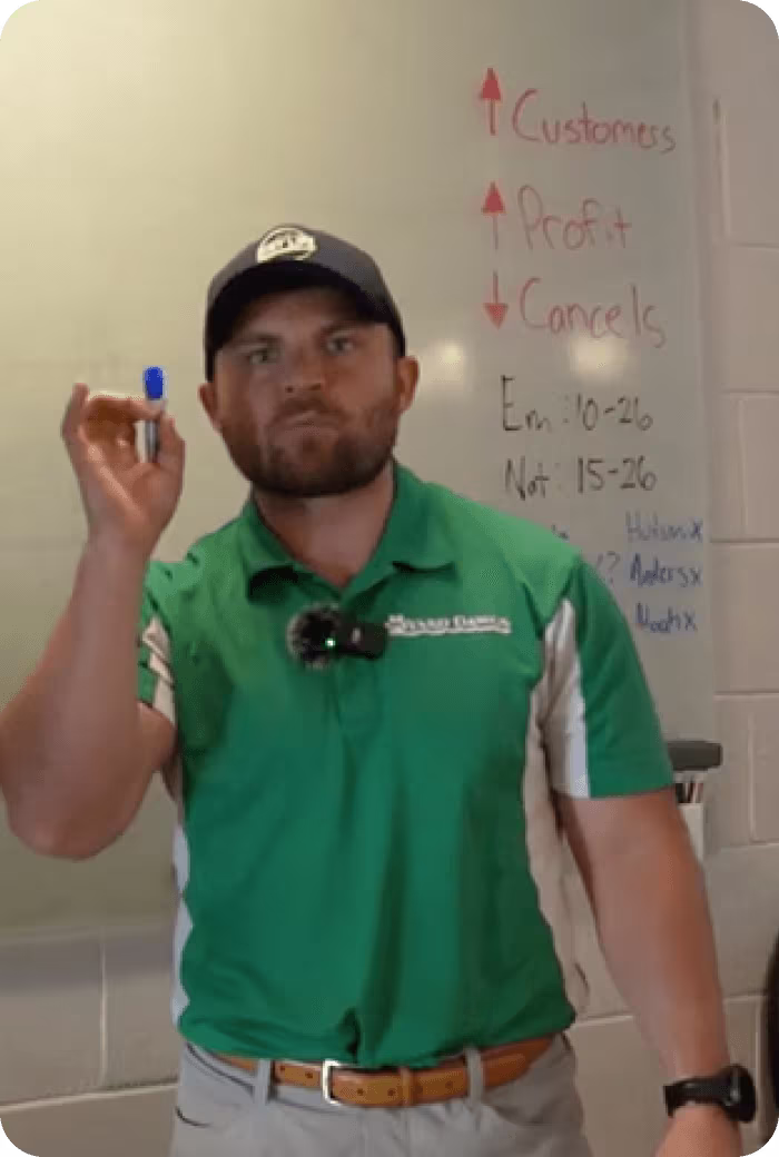 Employee in green polo presenting business metrics on whiteboard