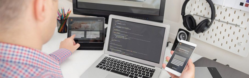 Developer working on multiple devices with code and design screens
