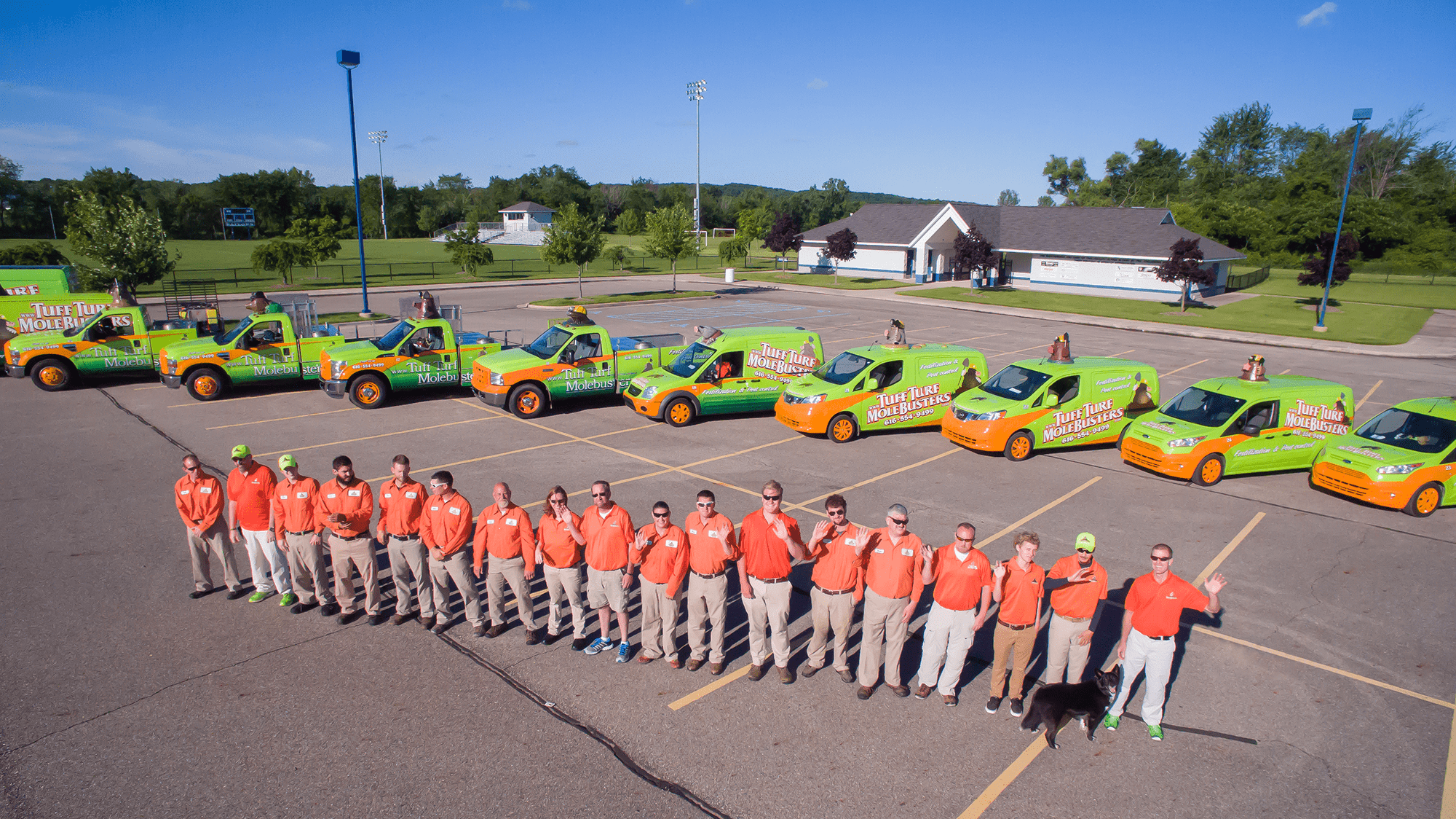 Tuff Turf Molebusters team with green and orange vehicles in parking lot