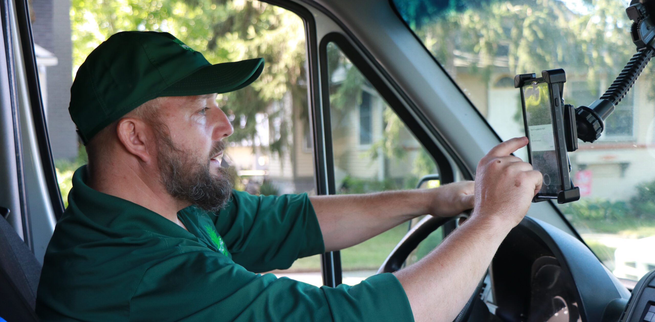 Delivery driver in green uniform using GPS navigation while driving van