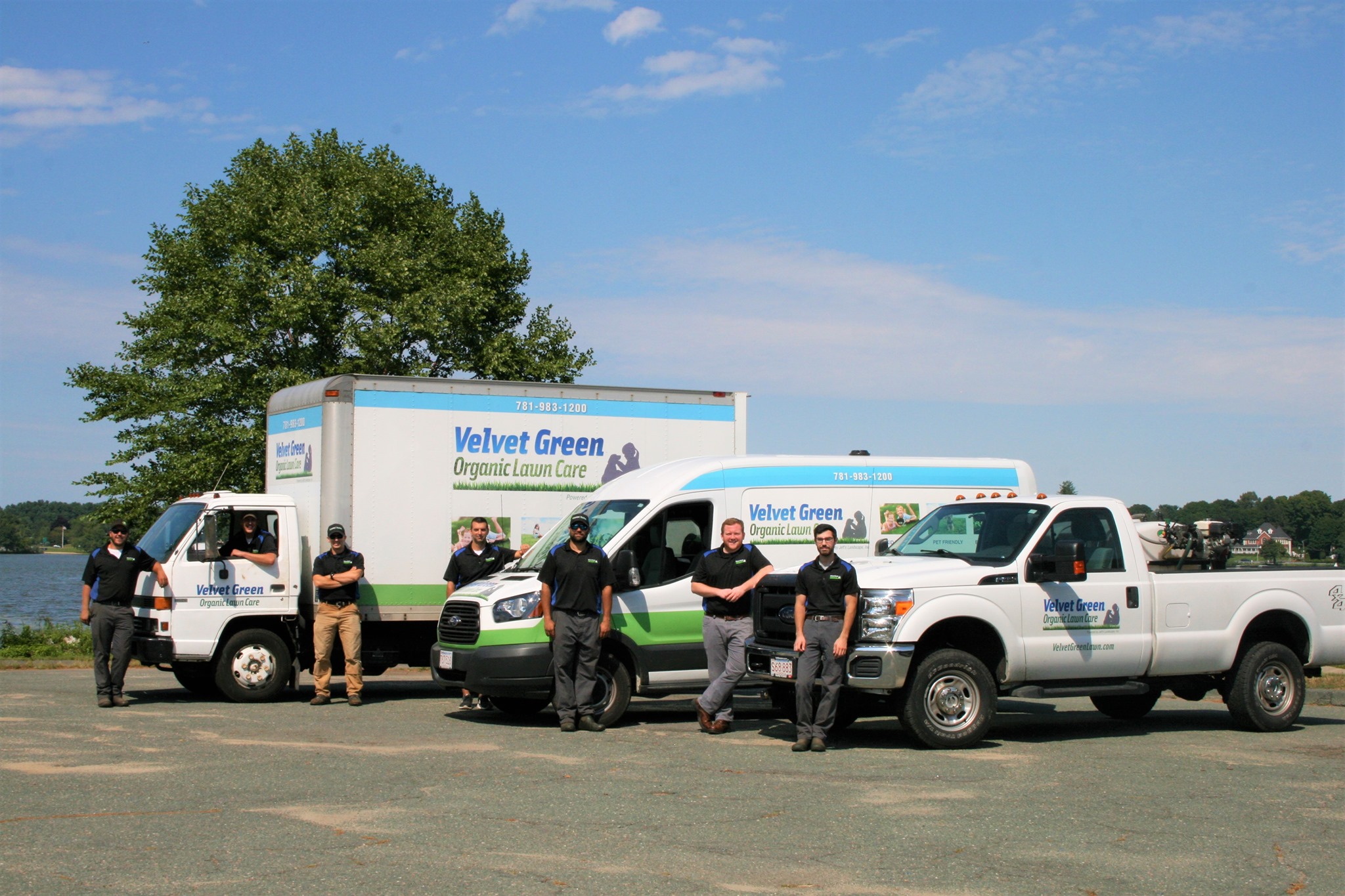 Velvet Green Organic Lawn Care team with vehicles by waterfront