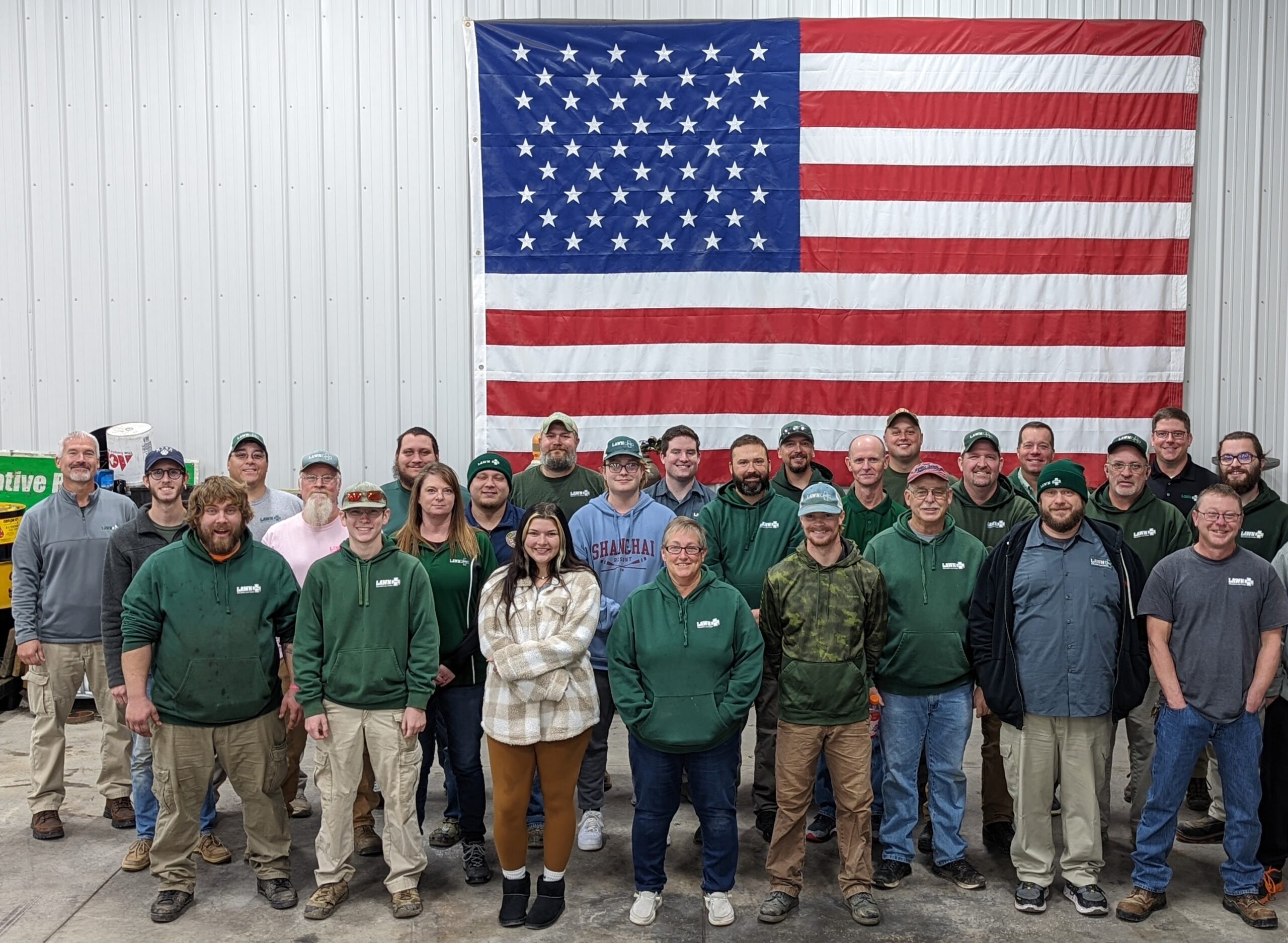 Company team photo with American flag, employees in green and gray uniforms
