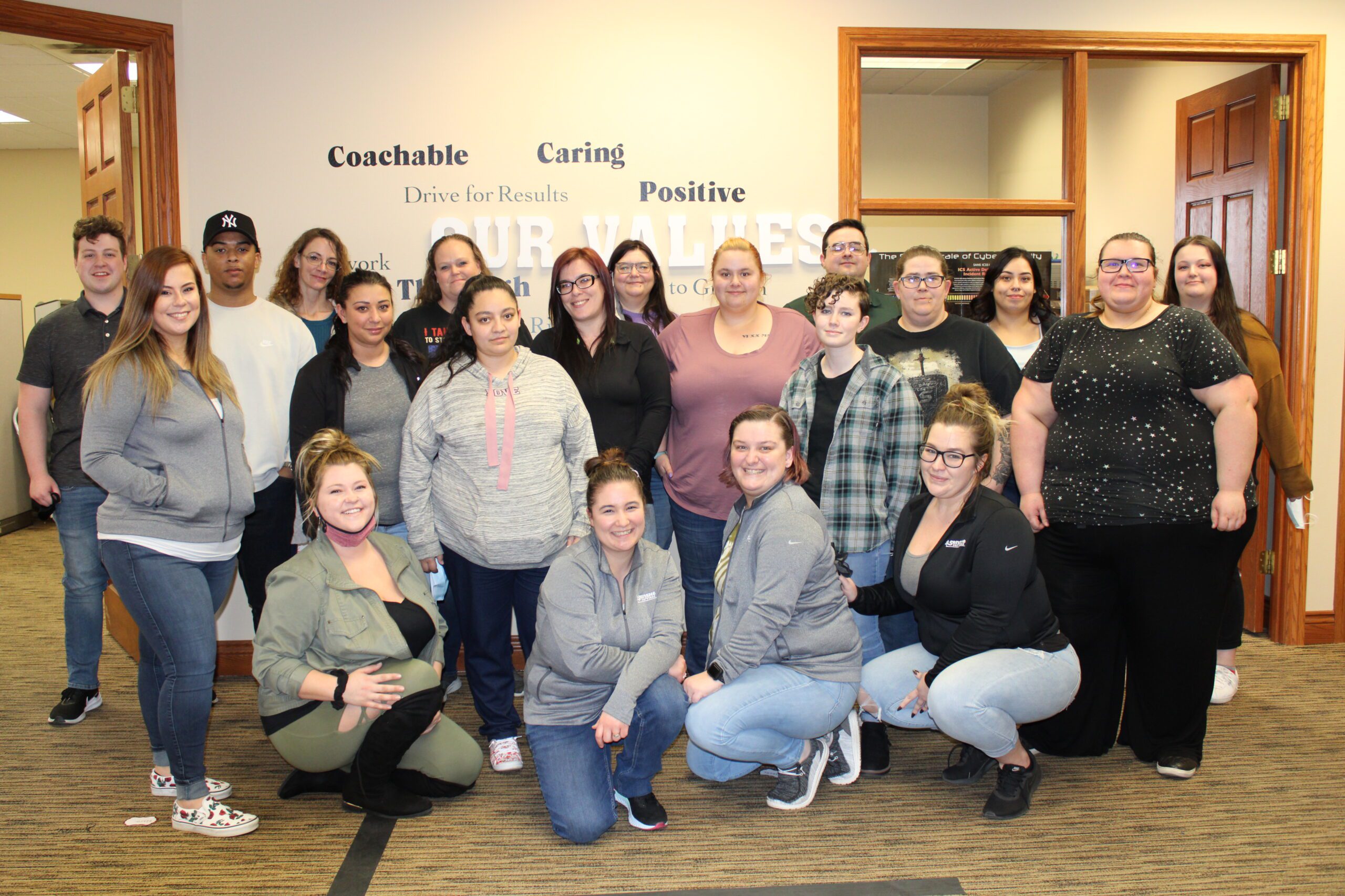 Large group photo of team in office with company values on wall