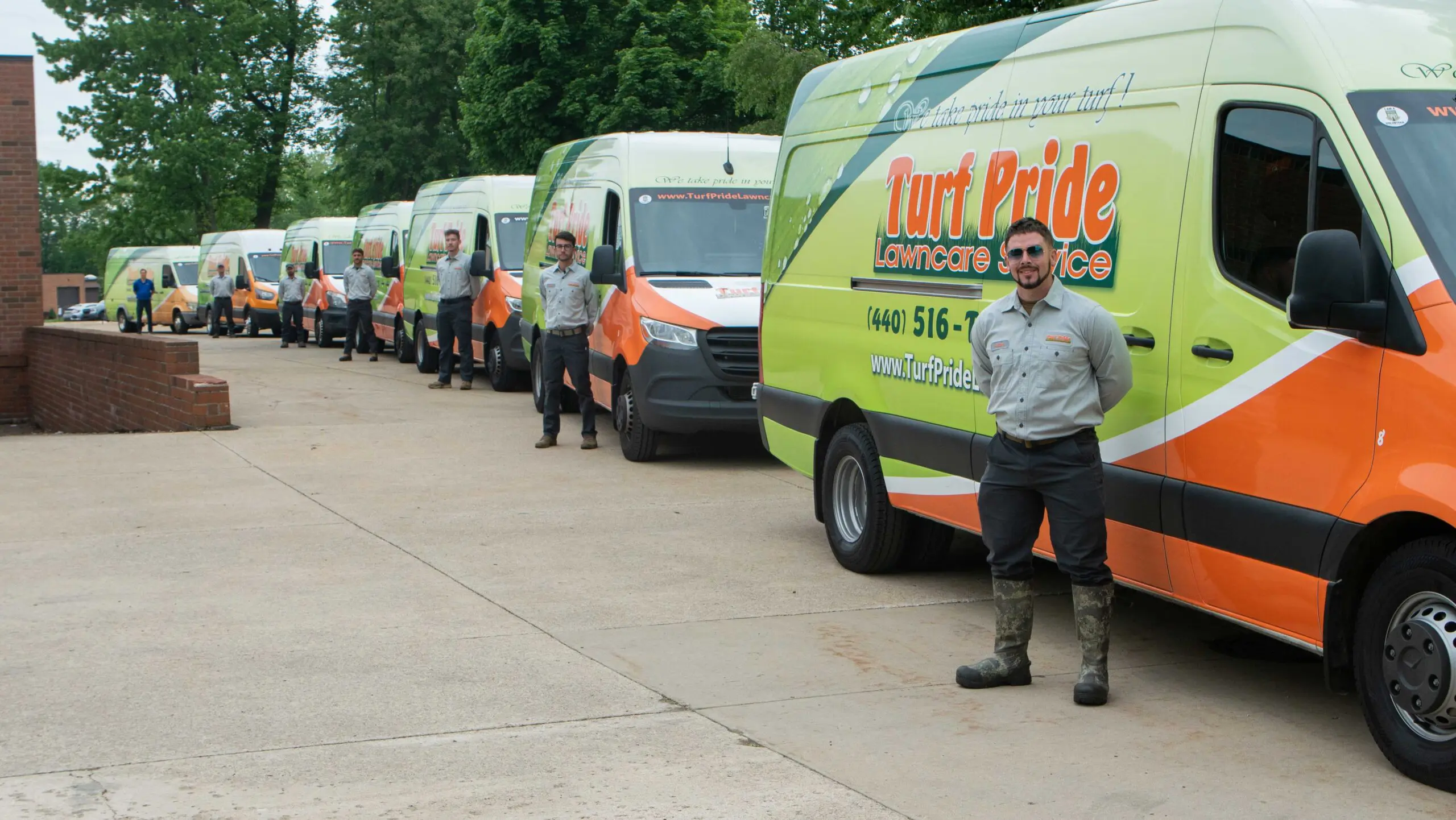 Turf Pride Lawn Care Service vehicles and employees lined up outside