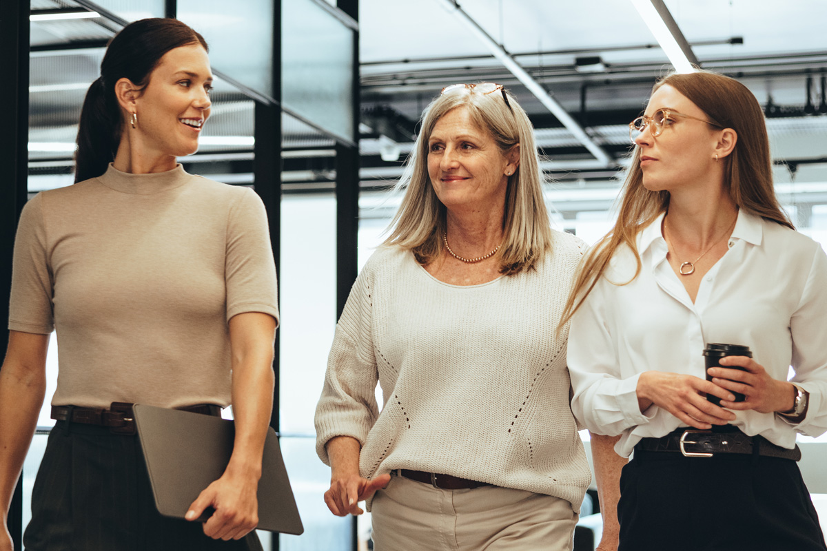 Three professional women talking in modern office with neutral clothing