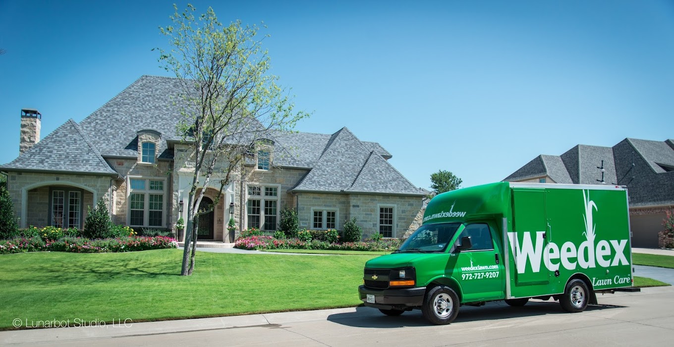 Green Weedex lawn care truck parked in front of large stone house