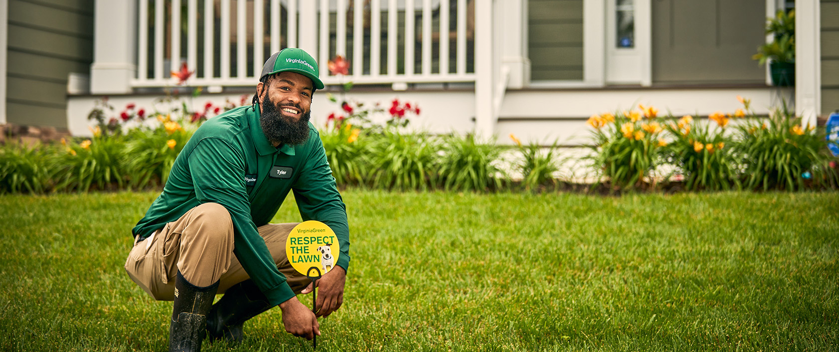 Lawn care professional in green uniform kneeling on grass with 'Respect the Lawn' sign