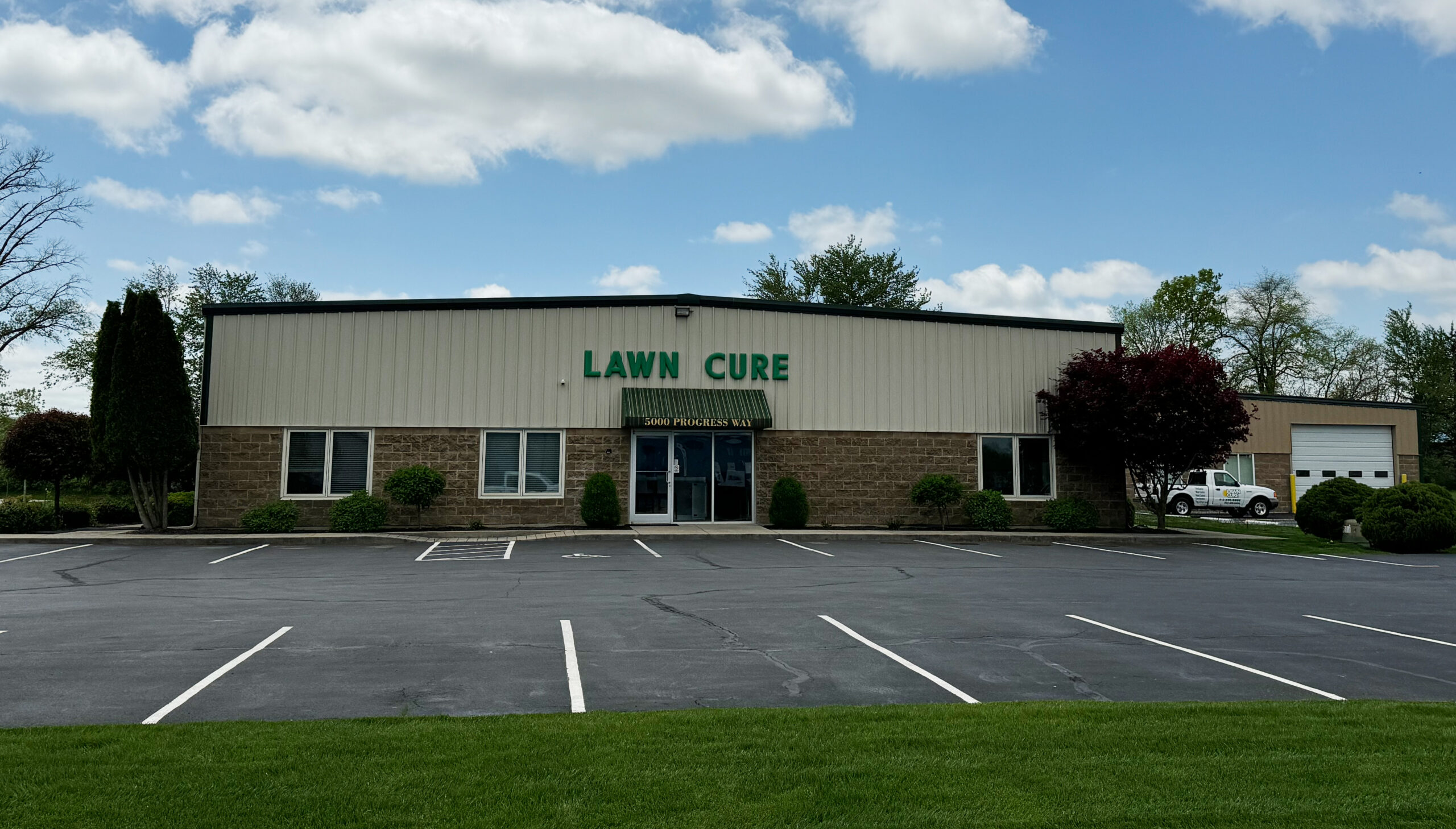 Lawn Cure business building with empty parking lot on sunny day