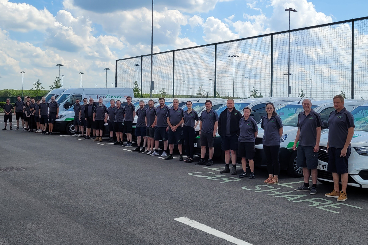 Work team standing in front of company vehicles on parking lot
