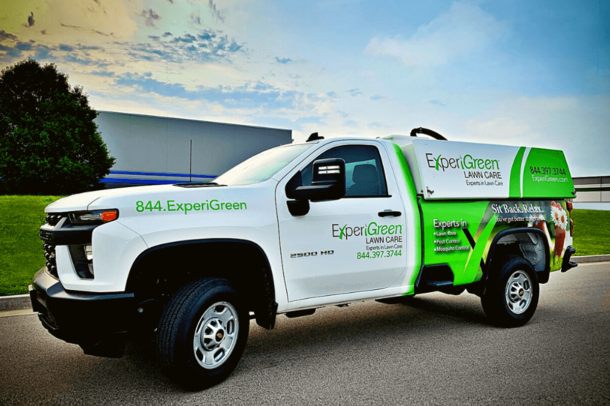 White and green ExperiGreen Lawn Care truck parked on asphalt