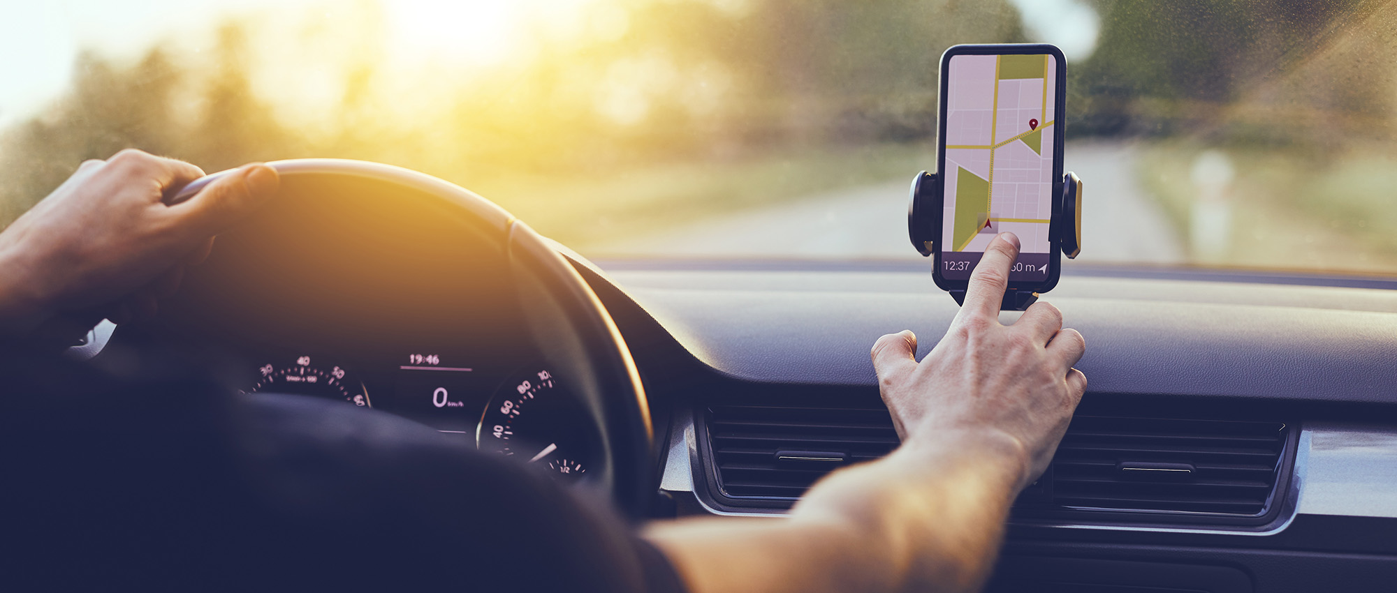 Driver using smartphone GPS navigation while driving on sunny day