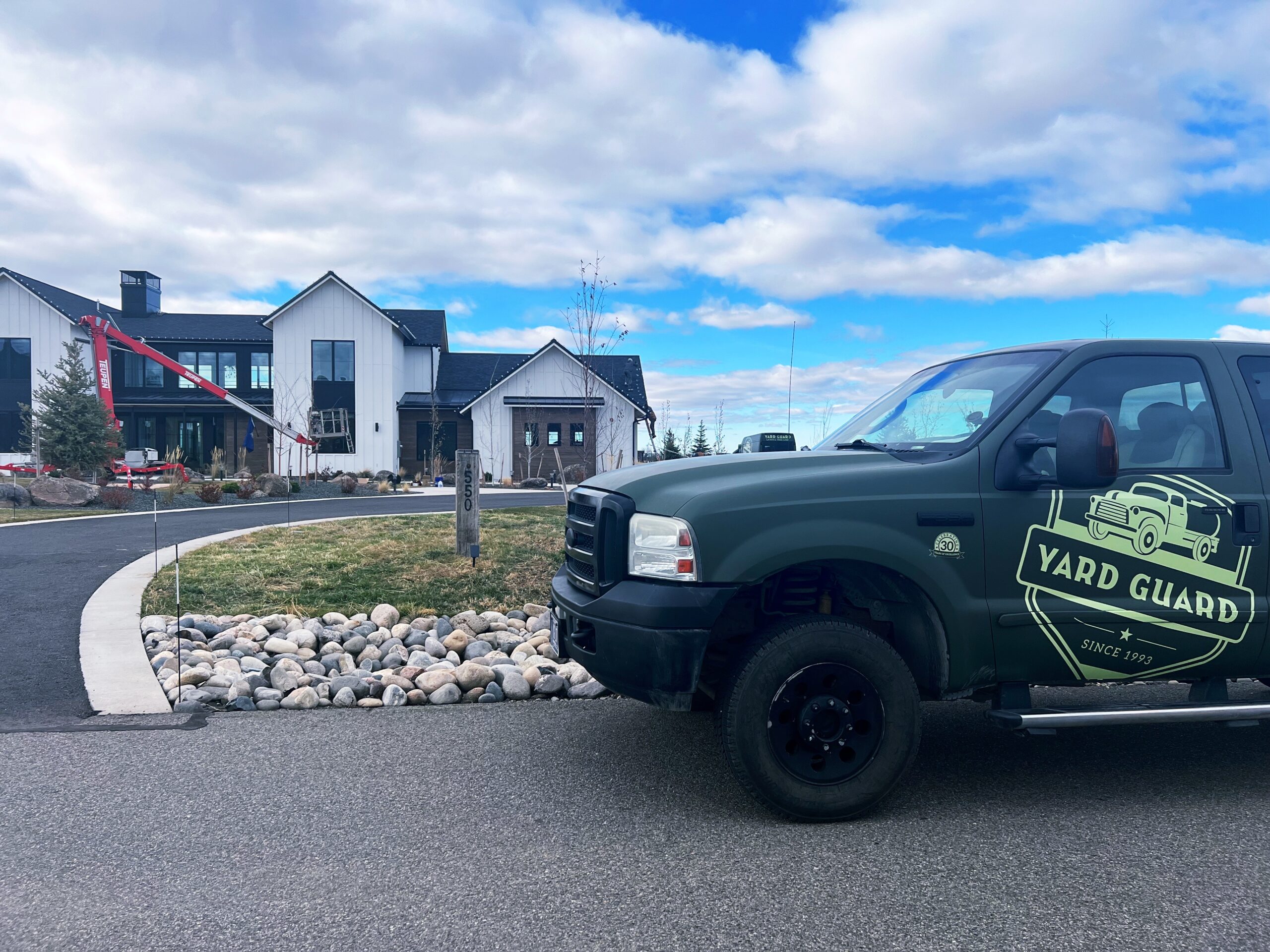 Yard Guard truck parked near modern houses with rocky landscaping