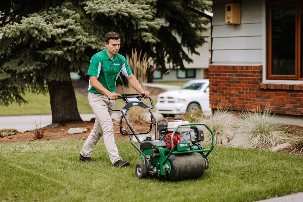 Landscaper using lawn roller to maintain grass in residential neighborhood