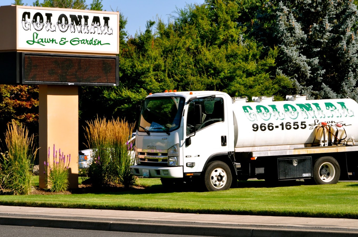 White Colonial Lawn & Garden truck parked in front of business sign