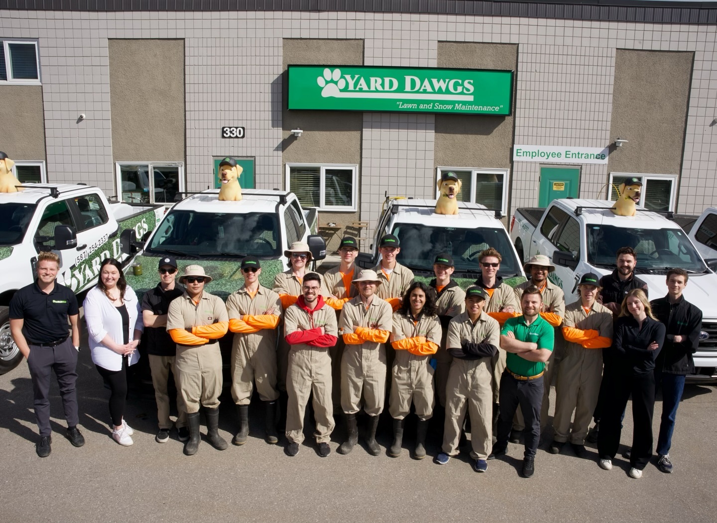 Yard Dawgs team photo with company trucks and golden dog statues