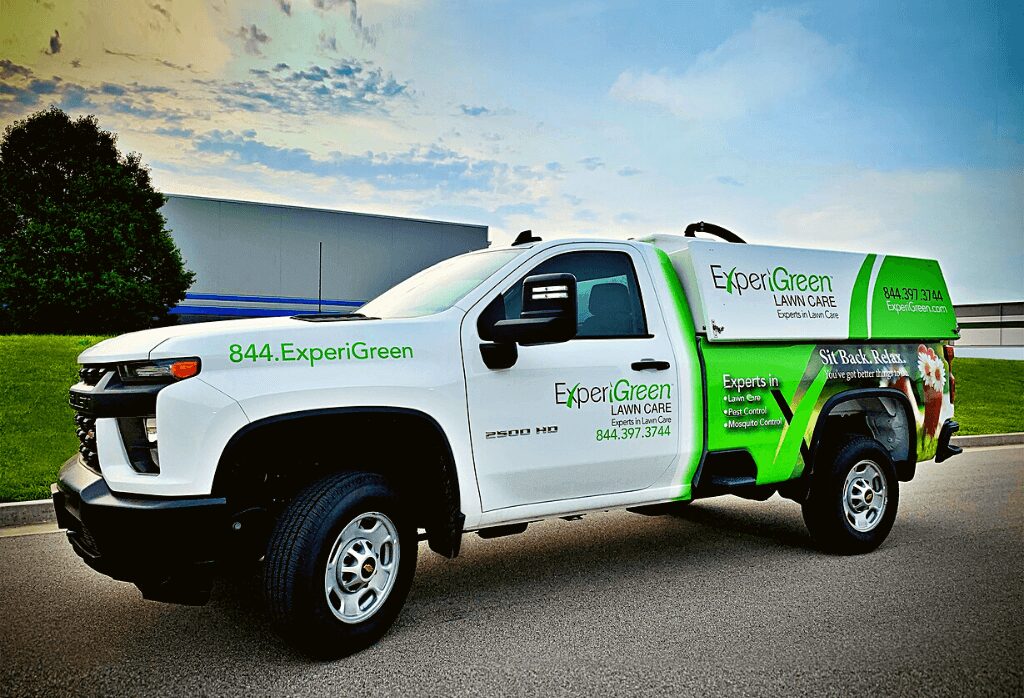 White and green ExperiGreen lawn care service truck parked outdoors