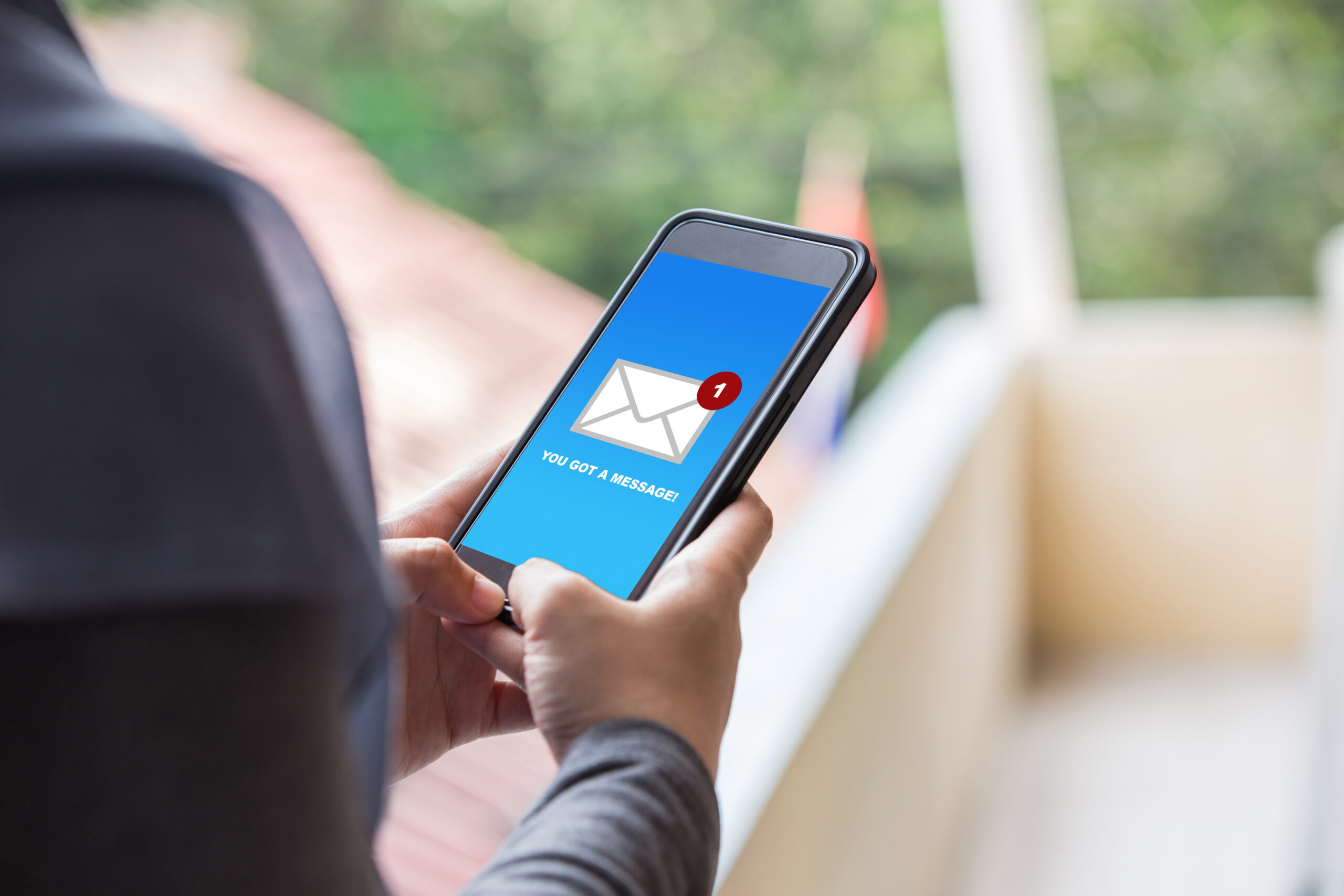 Person holding smartphone with new message notification on blue screen