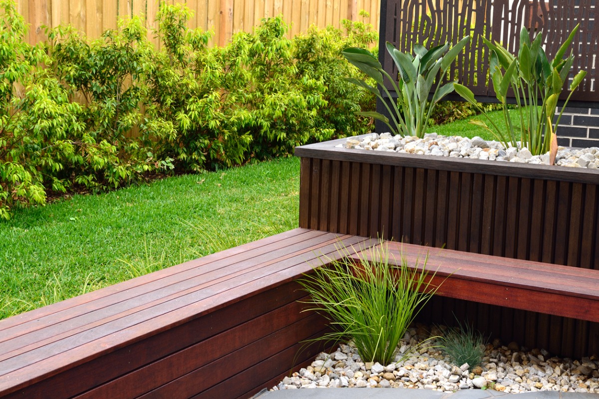 Modern garden with wooden bench, decorative rocks, and lush green plants