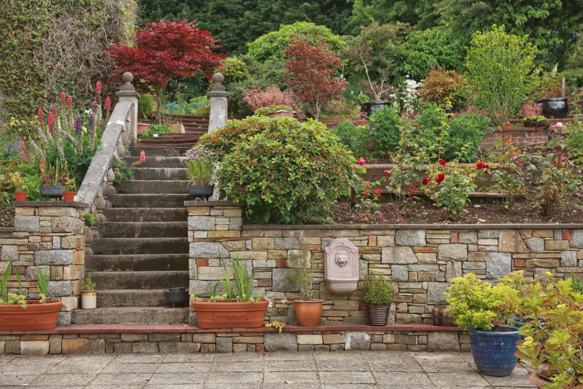 Multilevel garden with stone stairs, terraced flower beds, and colorful plants