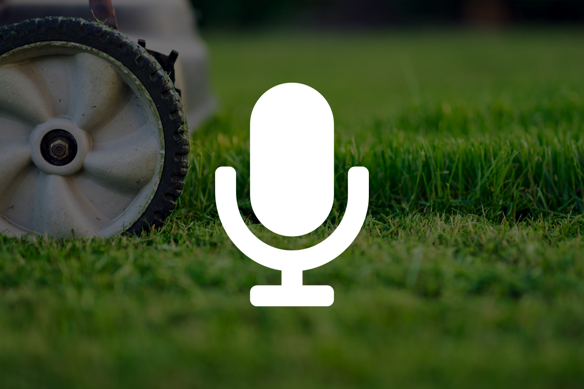 White microphone icon on lawnmower wheel and green grass background