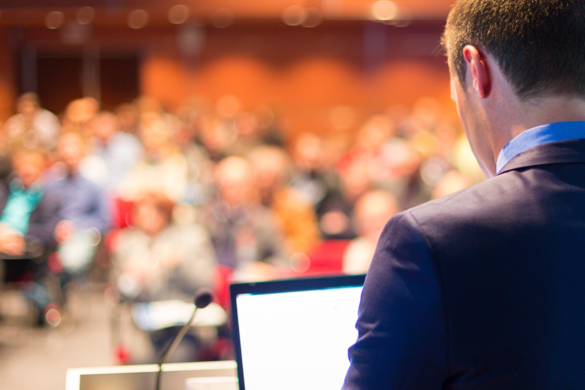 Speaker presenting to a large audience at a conference or business event
