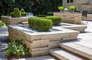 Modern garden with geometric stone planters and neatly trimmed green shrubs