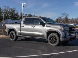 Silver pickup truck parked in lot with trees and streetlight in background