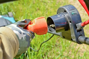Power drill connecting to attachable tool on grassy background