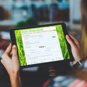 Person holding tablet with green website form and grass background