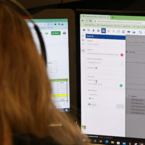 Person working on computer screens with spreadsheet and document open