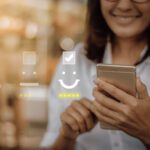 Smiling person holding phone with glowing emoji hologram projection