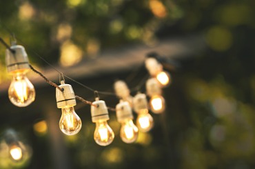 Warm glowing string lights hanging outdoors with soft bokeh background