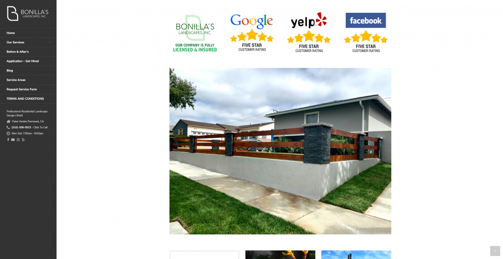 Modern wood and stone fence with green lawn and concrete walkway