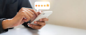 Hand giving five-star rating on smartphone screen