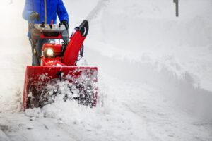 Red snow blower clearing deep snow on a winter day