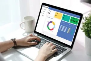 Person working on laptop with analytics dashboard and coffee mug nearby