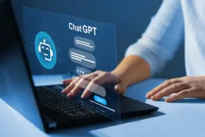 Hands typing on laptop with ChatGPT logo and interface displayed