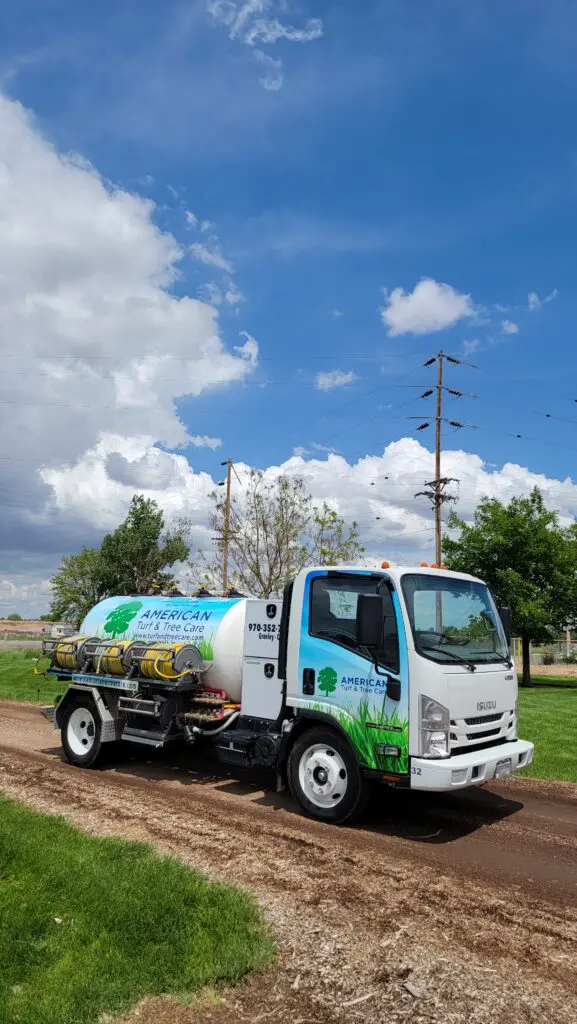 American Tree Care truck parked on dirt road with blue sky and clouds