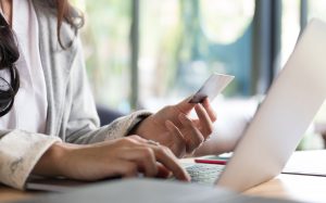 Person working on laptop and smartphone at modern workspace